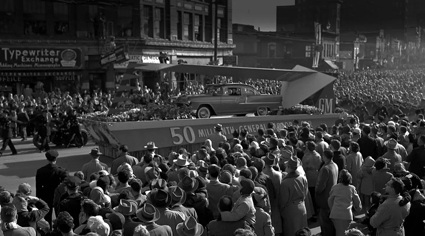 Black and white photo of crowd of people viewing GM car